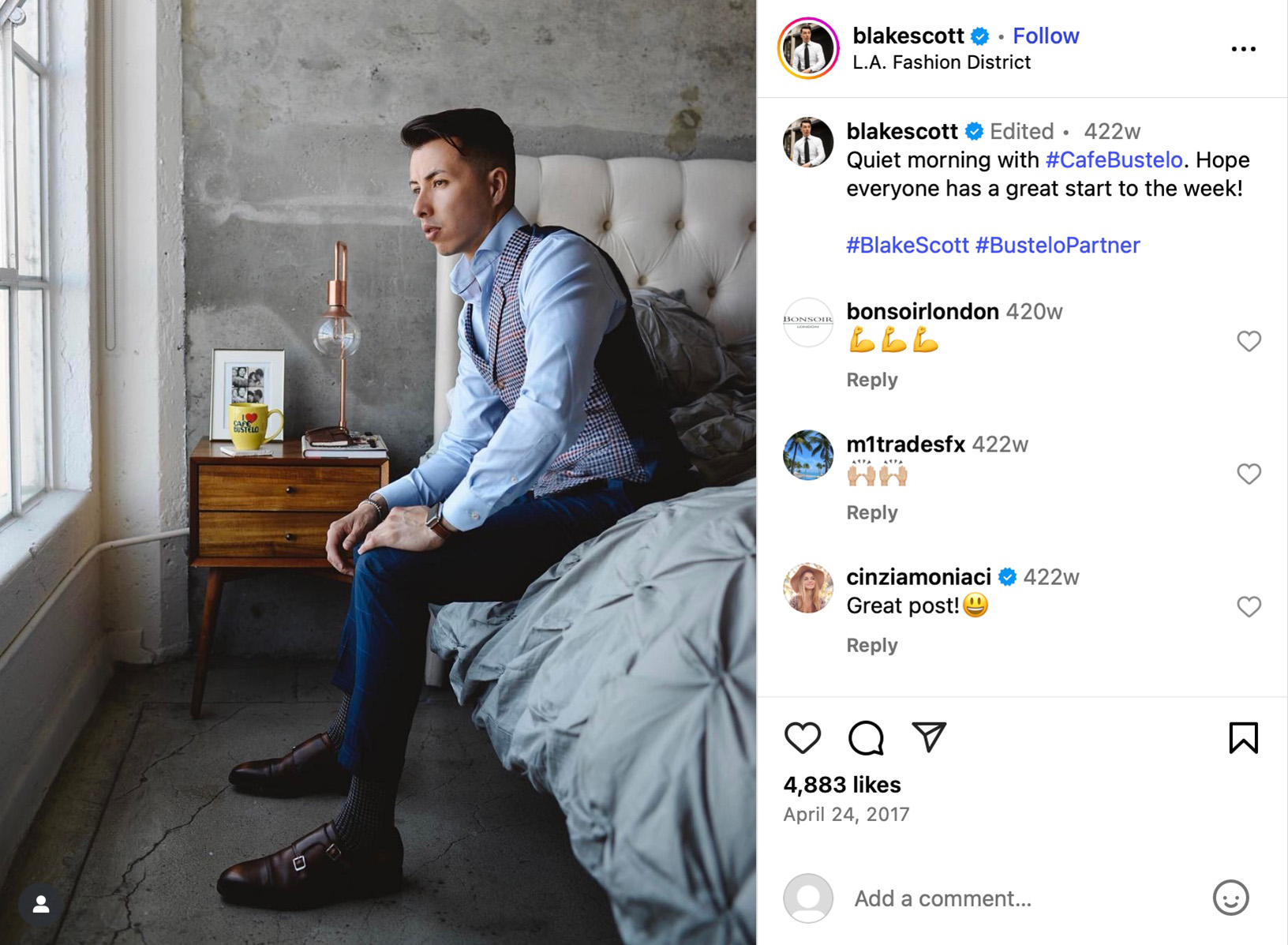 Blake Scott partners with Cafe Bustelo for morning style post Blake Scott sitting on a bed in a tailored outfit, looking out a window with a Cafe Bustelo mug on the nightstand