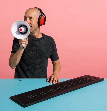 Brian Hazard holding a megaphone posing with a ROLI Seaboard
