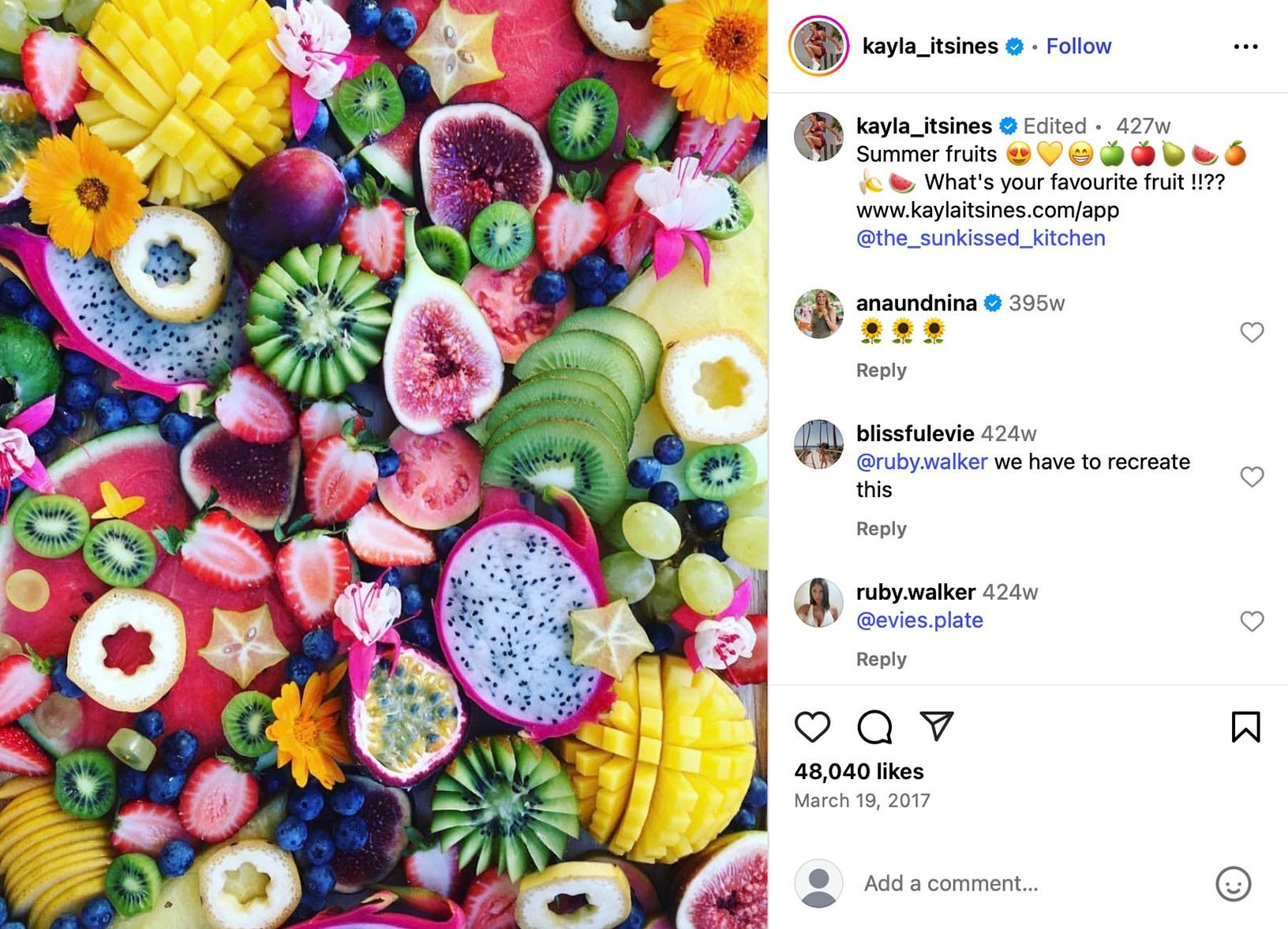 Kayla Itsines celebrates summer with vibrant fruit spread Flat lay of colourful tropical fruits like dragonfruit, kiwi, mango, and figs styled with flowers