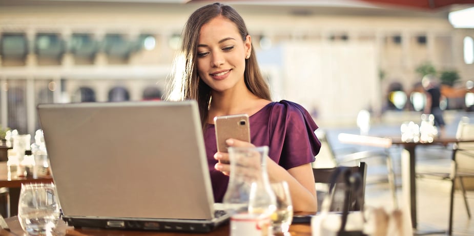 Person distracted from laptop computer by looking at mobile phone