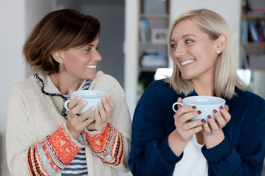 Two people holding mugs facing each other