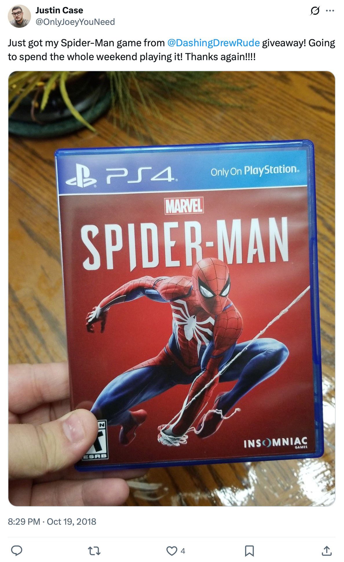 Hand holding Marvel Spider-Man PS4 game case over wood table